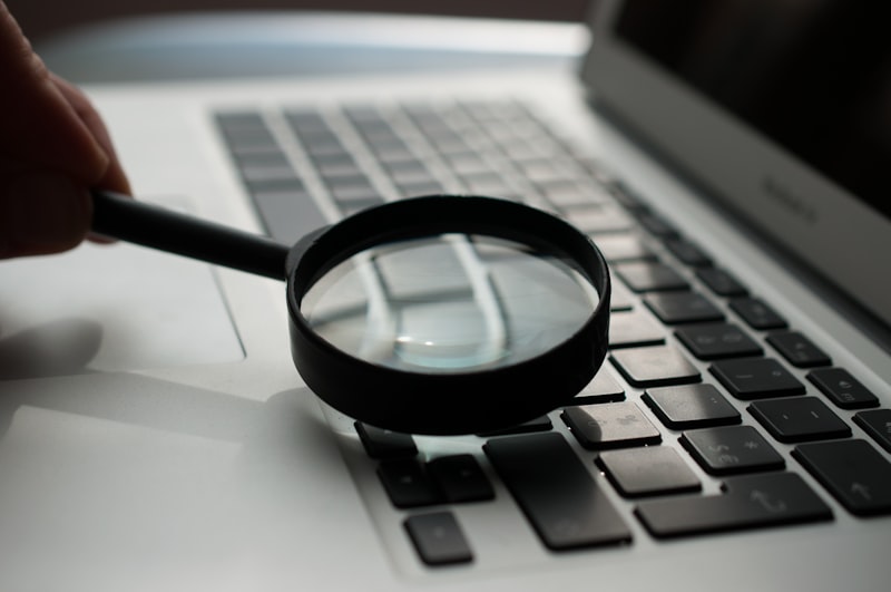 Lupa junto a portátil representando auditoría forense de datos